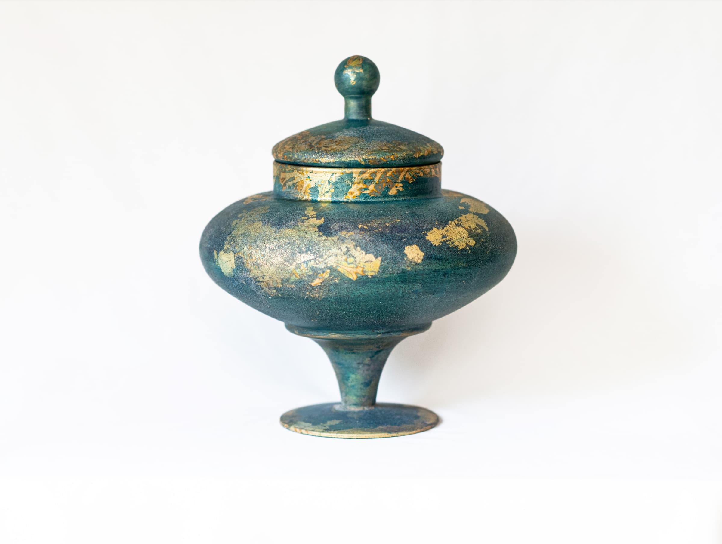 Close view of a rounded teal memorial vessel with hand-applied gold leaf